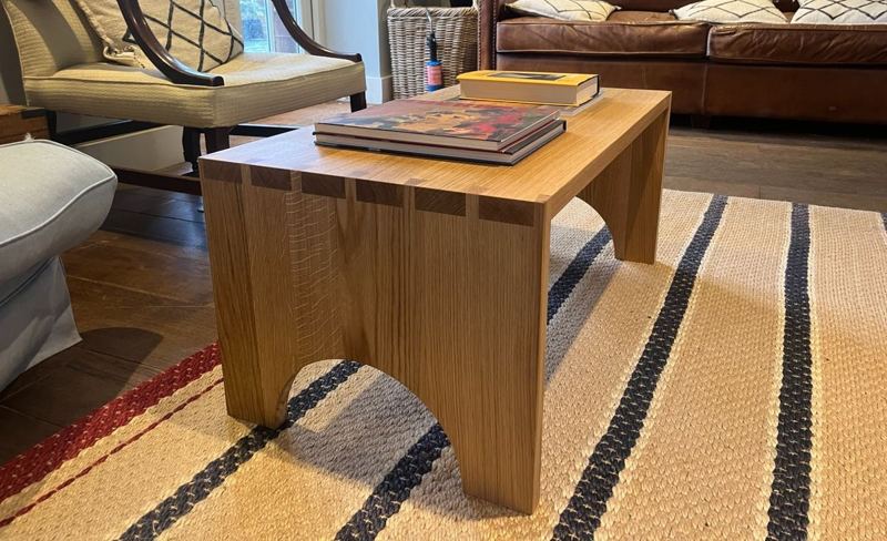 Oak coffee table in situ — through-dovetails and arch visible